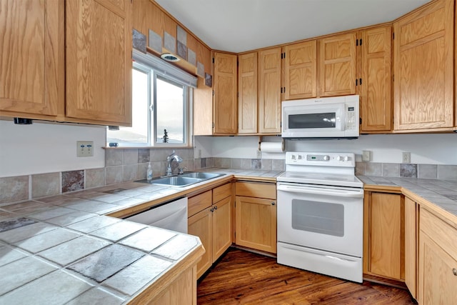 kitchen with a sink, tile counters, white appliances, and dark wood finished floors