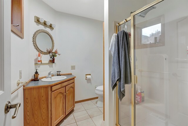 bathroom featuring toilet, vanity, tile patterned floors, and a shower with shower door