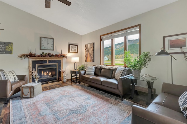 living room with wood-type flooring, ceiling fan, a tile fireplace, and vaulted ceiling