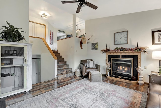 living room featuring ceiling fan, vaulted ceiling, dark hardwood / wood-style floors, and a tiled fireplace