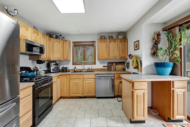 kitchen with light tile patterned flooring, appliances with stainless steel finishes, sink, and a healthy amount of sunlight