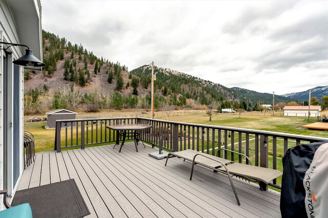 wooden deck with a lawn, a shed, a mountain view, and a grill