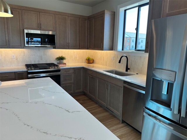 179 E Monture Rdg, Kalispell, MT 59901 - kitchen with stainless steel appliances, light wood-type flooring, light stone counters, and backsplash