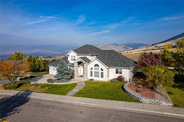 view of front facade featuring a front yard, a mountain view, and a garage