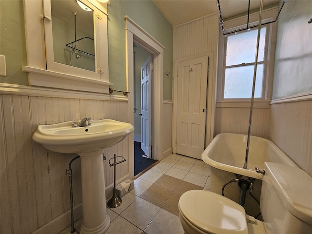 bathroom featuring a tub, tile patterned flooring, wooden walls, and toilet