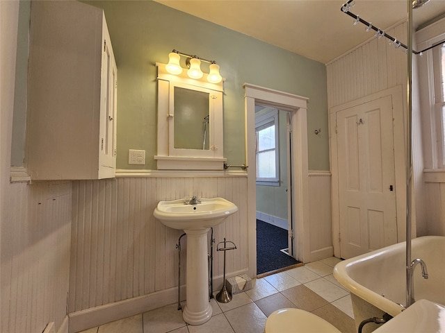 bathroom with wood walls, a tub to relax in, sink, and tile patterned flooring