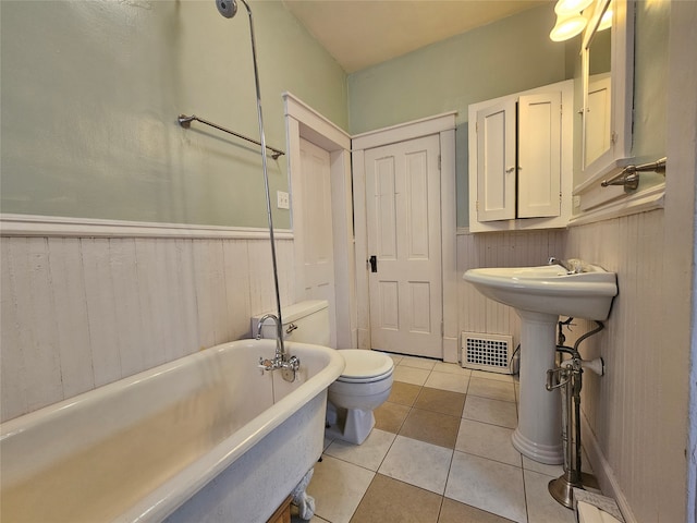 bathroom with toilet, a washtub, wooden walls, and tile patterned floors