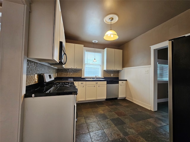 kitchen featuring appliances with stainless steel finishes, decorative light fixtures, decorative backsplash, sink, and white cabinets