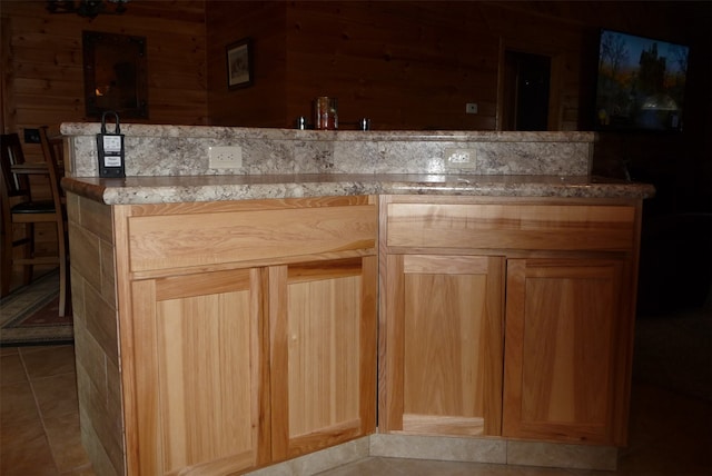 kitchen with light brown cabinets, wooden walls, and light tile patterned floors