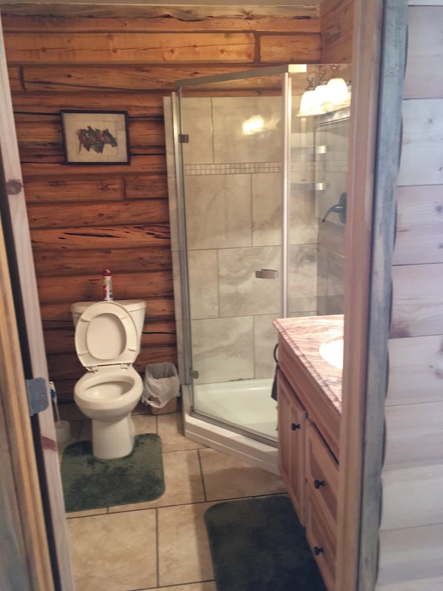 bathroom with toilet, tile patterned flooring, wood walls, an enclosed shower, and vanity