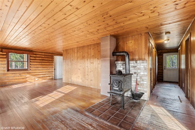 unfurnished living room featuring a wood stove, hardwood / wood-style floors, and a healthy amount of sunlight