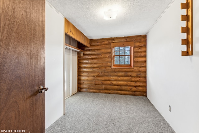 empty room featuring a textured ceiling, log walls, and carpet floors