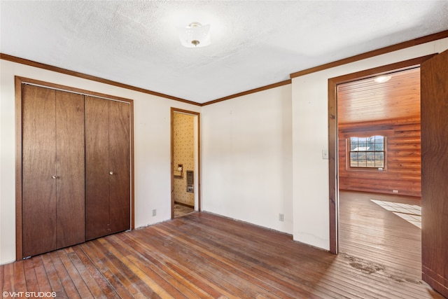 unfurnished bedroom featuring dark wood-type flooring, a textured ceiling, a closet, and crown molding