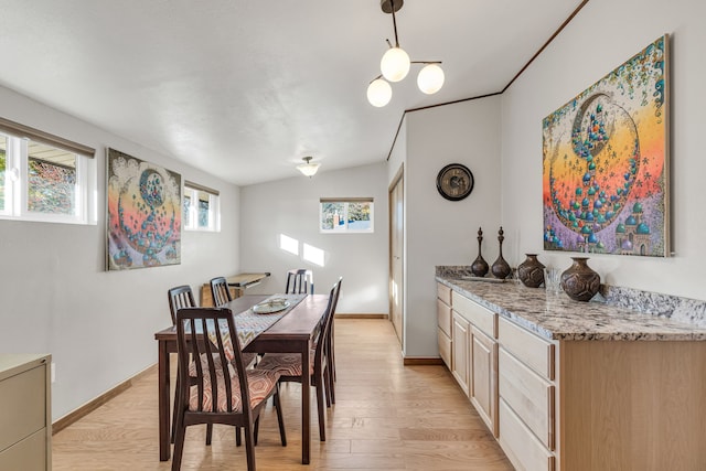 dining room featuring light wood-type flooring and vaulted ceiling