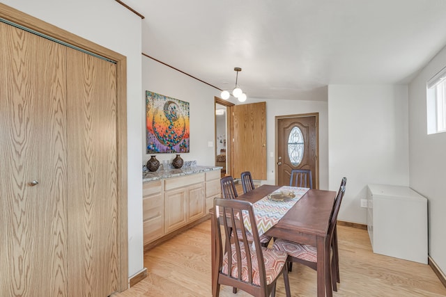 dining area featuring light hardwood / wood-style flooring, lofted ceiling, and an inviting chandelier