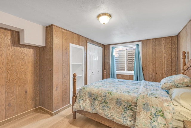 bedroom with light wood-type flooring and wooden walls