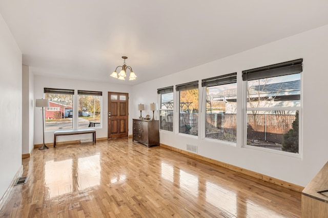 interior space with a wealth of natural light, hardwood / wood-style floors, and a notable chandelier