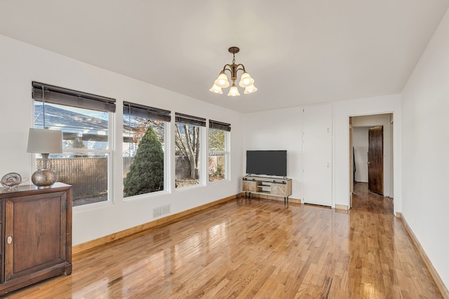 unfurnished living room with a chandelier and light hardwood / wood-style floors