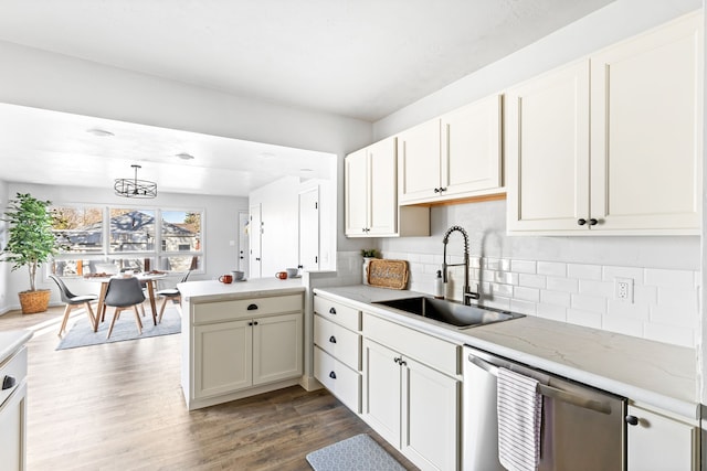 kitchen featuring tasteful backsplash, stainless steel dishwasher, dark wood-type flooring, sink, and decorative light fixtures