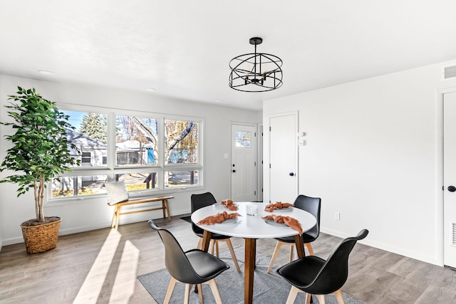 dining space with a wealth of natural light, a notable chandelier, and light wood-type flooring