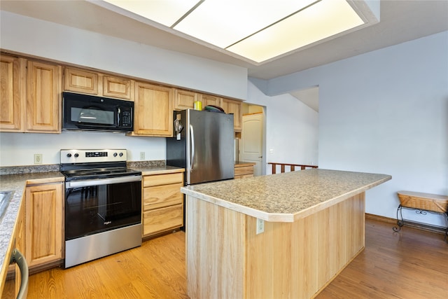 kitchen with appliances with stainless steel finishes, light hardwood / wood-style flooring, and a center island