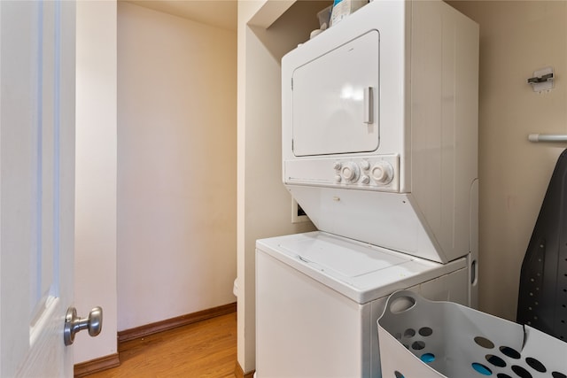 clothes washing area featuring stacked washing maching and dryer and light hardwood / wood-style flooring