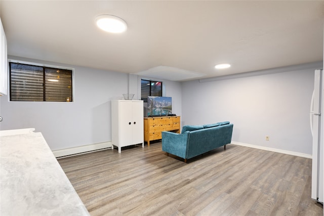 living area with sink, a baseboard radiator, and hardwood / wood-style flooring