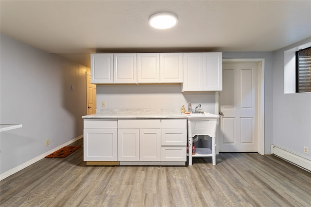 kitchen featuring baseboard heating, light hardwood / wood-style flooring, and white cabinetry