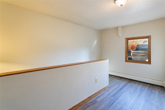 spare room with baseboard heating and hardwood / wood-style floors