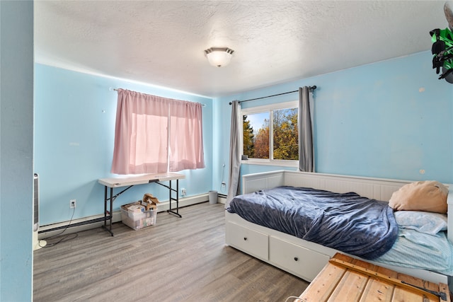 bedroom featuring a baseboard radiator, a textured ceiling, and hardwood / wood-style flooring