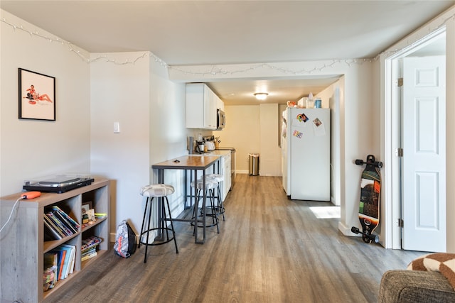 kitchen featuring light hardwood / wood-style floors, white cabinetry, white refrigerator, stove, and a kitchen breakfast bar