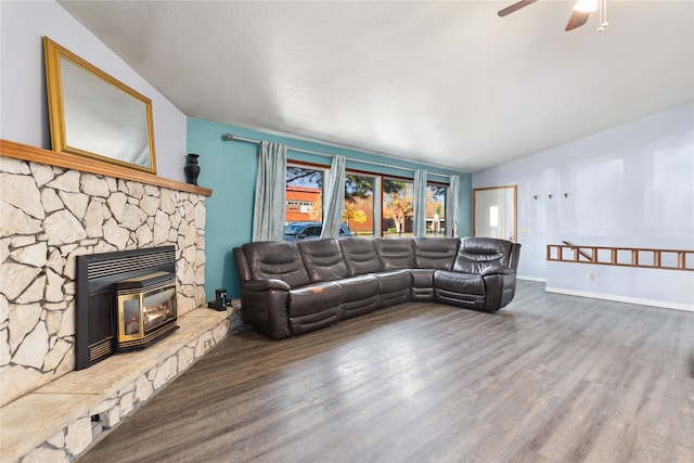 living room with ceiling fan, a stone fireplace, and dark hardwood / wood-style floors