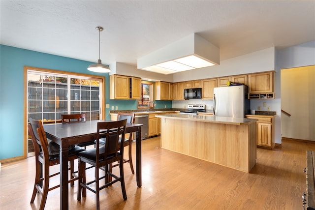 kitchen featuring sink, a center island, light hardwood / wood-style floors, pendant lighting, and appliances with stainless steel finishes