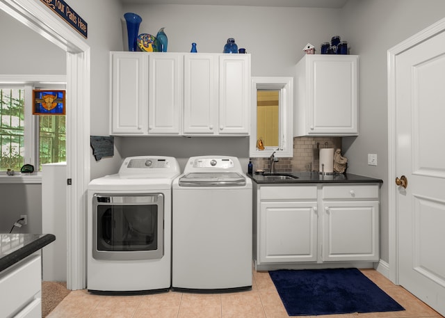 clothes washing area featuring cabinets, sink, light tile patterned floors, and washing machine and clothes dryer