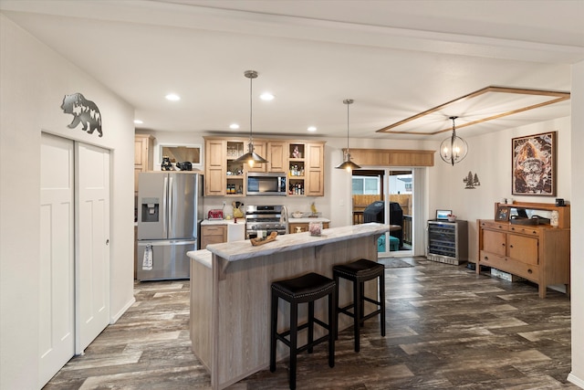 kitchen featuring a kitchen island, appliances with stainless steel finishes, decorative light fixtures, light brown cabinets, and a breakfast bar