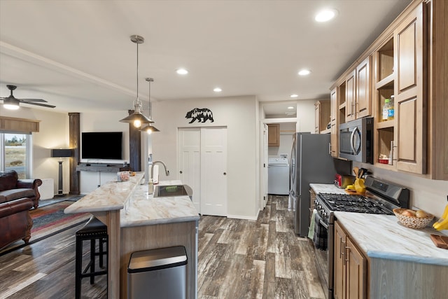 kitchen featuring a center island with sink, appliances with stainless steel finishes, dark hardwood / wood-style floors, hanging light fixtures, and sink