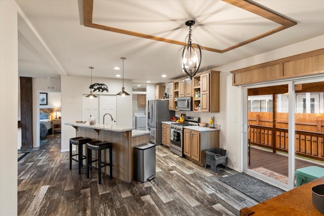 kitchen featuring a center island with sink, appliances with stainless steel finishes, decorative light fixtures, dark hardwood / wood-style floors, and a breakfast bar area