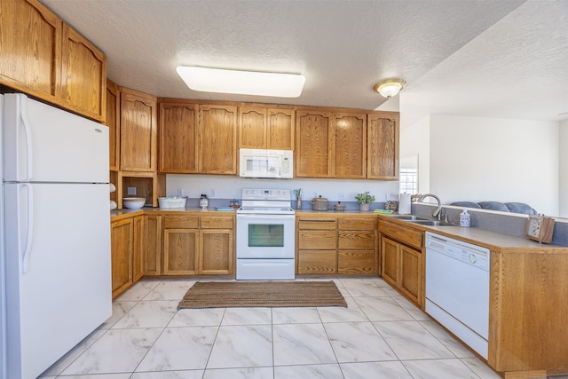 kitchen featuring white appliances, a textured ceiling, sink, and kitchen peninsula