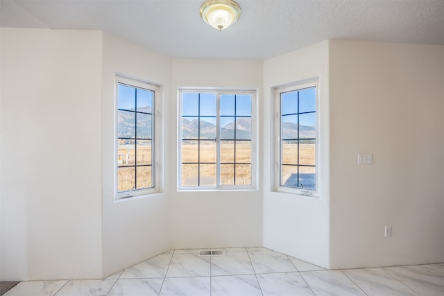 empty room with a textured ceiling and a mountain view