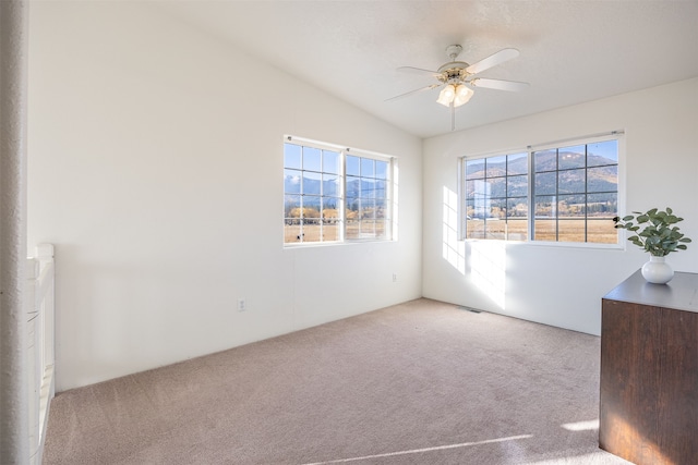 carpeted empty room featuring ceiling fan, plenty of natural light, and lofted ceiling