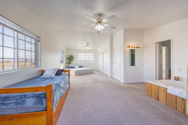 carpeted bedroom featuring ceiling fan, multiple windows, a textured ceiling, and vaulted ceiling