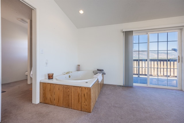 bathroom featuring a tub, toilet, and lofted ceiling