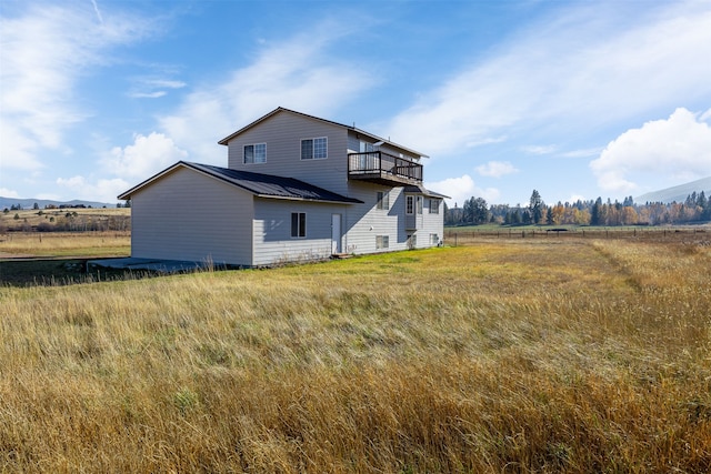 rear view of house with a rural view and a balcony