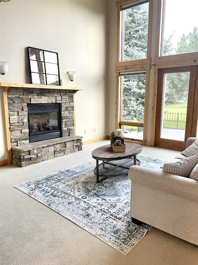 carpeted living room with a fireplace, a healthy amount of sunlight, and a towering ceiling