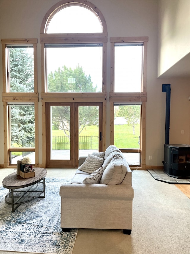 living room featuring a high ceiling, a wood stove, and plenty of natural light