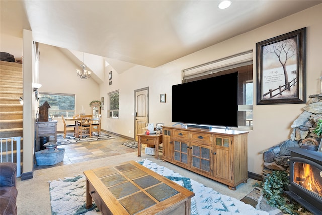 living room featuring light colored carpet, a wood stove, lofted ceiling, and a notable chandelier