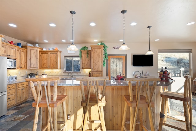 kitchen with decorative light fixtures, decorative backsplash, a breakfast bar, and stainless steel appliances