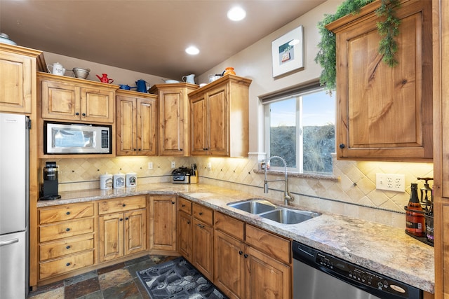 kitchen featuring decorative backsplash, sink, light stone counters, and stainless steel appliances