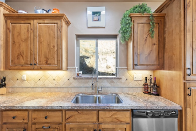 kitchen featuring stainless steel dishwasher, sink, light stone counters, and tasteful backsplash