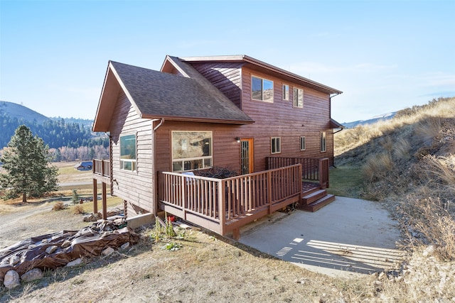 back of property featuring a deck with mountain view and a patio area